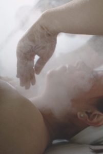a woman laying in bed with steam coming out of her stomach