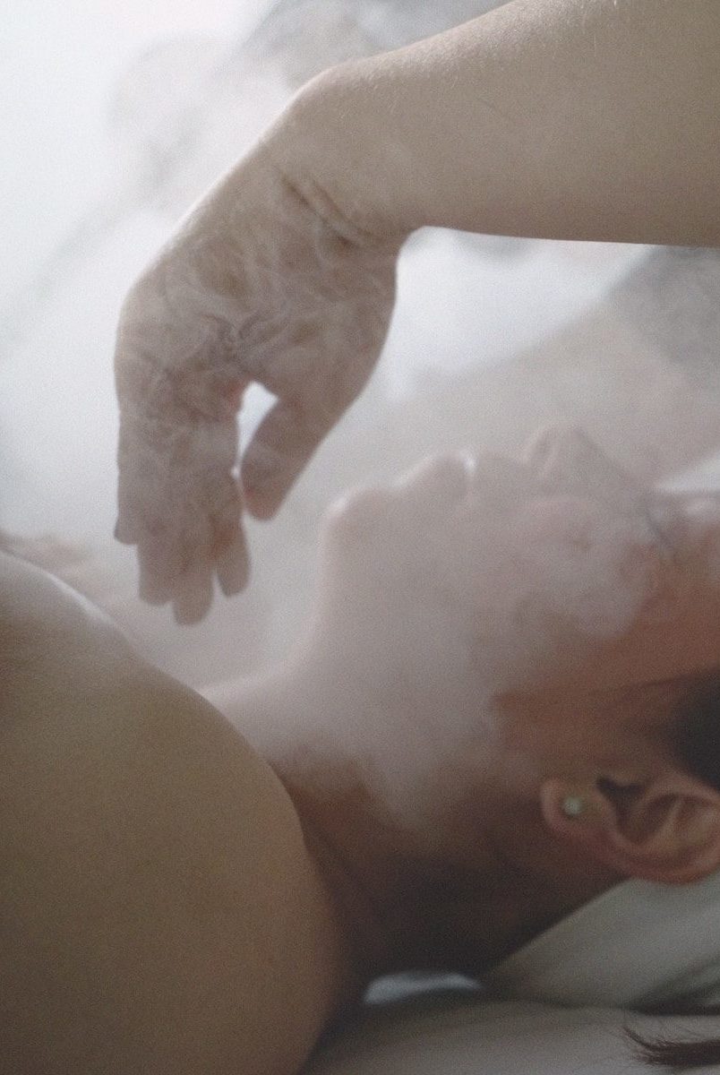 a woman laying in bed with steam coming out of her stomach